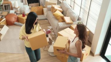 Asyalı bir çiftin taşınma gününde evde dans ederken ellerinde karton bir kutu tutuşu. Çekici lezbiyen çift yeni eve taşınırken bir yandan da müzik eşliğinde taşınıyor. Myrmidon.