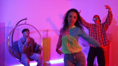 İspanyol hipster renkli kıyafetler giyer ve serbest stil müziğe el sallar. Profesyonel break dansçı neon ışıklarıyla ve modern stüdyo arkadaşlarıyla coşkuyla dans ediyor. Mutluluk.