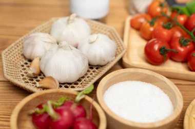 Sağlıklı gıdalarda ev yapımı turp, sarımsak, tuz, kekik, domates ve baharatlardan oluşan özel menü içerikleri, ahşap masayı bulanık arka plana yerleştirir. Varsayım.