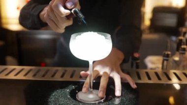 Yakın plan votka kokteyli ve Asyalı barmen gece kulübündeki lüks tezgahta şeker sunumuna ateş yakıyor. Gece hayatı karışımının sergilendiği özel bir içecek sıcak ışığı davet ediyor. Vinosity.