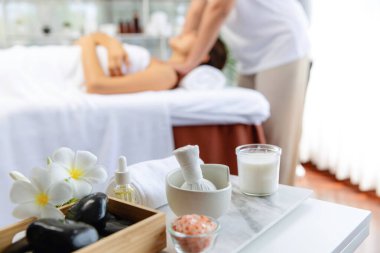 Aromaterapi masajı gündüz atmosferinde ya da spa salonunda bulanık bir kadına odak dekor ve spa aksesuarları kurarak tatil köyünde ya da otel arka planında keyifli aroma spa masajı yapan bir masaj. Sessiz.