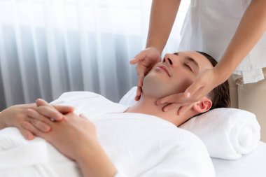Beyaz adam stres önleyici kafa masajından ve lüks bir tatil beldesi veya otel spa salonundaki modern ışık ortamında yüz güzelliği eğlencelerini şımartmaktan hoşlanıyor. Sessiz.