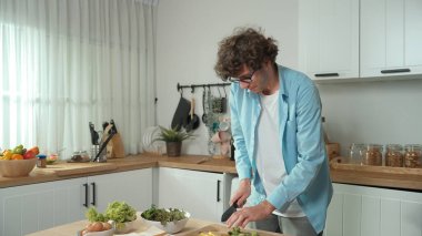 Mutlu baba yemek pişirirken müziğe geçiyor ve modern mutfakta öğle yemeği hazırlıyor. Aktif baba, sebze ve mutfak gereçleri ile çevrili sağlıklı yemek ya da salata yaparken şarkıyla dans ediyor. Pedagoji.