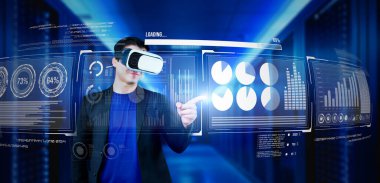 Finansal verileri analiz ederken veri merkezinde duran kulaklıklı bir iş adamı. Yönetici, pazarlama istatistiksel hologramını işaret ediyor ve karar verirken artırılmış gerçeklik gözlükleri kullanıyor. Yaratıcılık.