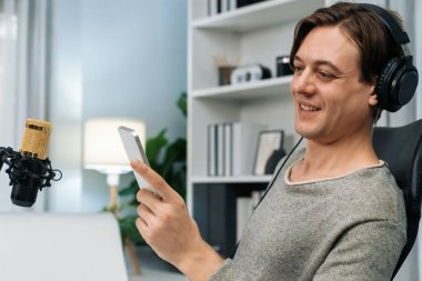 Akıllı yayıncının sunucu kanalı canlı sosyal medya yayını ile akıllı telefon kullanarak dinleyiciyle sohbet ediyor, kulaklık takarak modern ev stüdyosunda video kaydediyor. Bireysel.