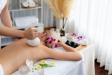 Sıcak bitkisel top spa masaj vücut tedavisi, masör kadın vücuduna nazikçe şifalı bitki torbası bastırıyor. Aromaterapi dinlenme sükuneti ve sükuneti kaplıca salonundaki atmosferi aydınlatıyor. Sessiz.