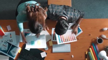 Tasarımcı yazma fikri ekrana bakarken proje yöneticisinin üst görünümü. Akıllı iş adamlarını kapat ve tasarımcı palete bakarken logo tasarımı fikrini açıkla. Sempozyum.