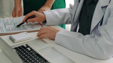 Hastane masasında birlikte çalışan ve tıbbi tedavi planlayan çeşitli profesyonel sağlık görevlileri. Takım çalışması başarılı hastalıklara ve hastalıklara yol açar. Ağır çekim. Katı.