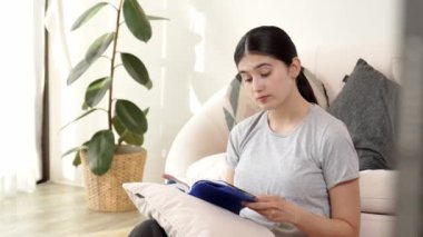 Kanepede oturan bir kadın ders kitabı okuyarak sosyal ve mesleki teknoloji bilgisini artırır ya da akıllı bir anne olmak için çocuk yetiştirir. Hayat boyu öğrenme konsepti. Uyumsuzluk.