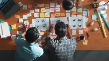 İşletme ekibinin üst görüntüsü toplantı masasına renkli yapışkan notlar ve tasarım ile grafik logo yazarak fikri açıklar. Proje yöneticisi fikri paylaşıyor ve akıllı takıma konsept sanatı anlatıyor. Sempozyum.