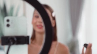 Sosyal medya için güzellik ve kozmetik video içeriği hazırlayan genç bir kadın. Güzellik blogcusu kameraya gülümserken seyircilere ve takipçilere güzellik bakımını gösteriyor. Düzenle