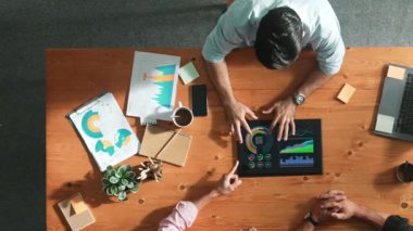 İş adamının üst düzey görüşü, bir grup akıllı yatırımcıya finansal grafik sunuyor. Profesyonel erkek lider grafiği analiz eder ve pazarlama fikrini toplantı masasında tablet kullanarak açıklar. Cemaat.