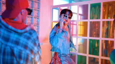 Ortasında dans eden profesyonel mutlu hipster onu alkışlayan çeşitli arkadaşlarıyla dans ediyor. Çekici Asyalı kırığı gece kulübünde neon ışığıyla enerjik adımlar atıyor. Mutluluk.