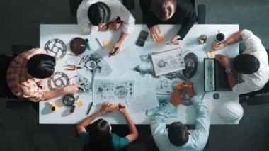 Üstten görünüşlü akıllı mühendis ekibi metal teçhizatlı, hesap makineli, yapışkan notlu türbin motor yapısı hakkında konuşuyor. Bir grup teknisyen toplantıda not alıyor. Hizalama.