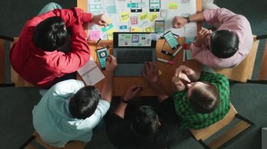 Akıllı yaratıcı proje yöneticisinin cep telefonu arayüzü için dizüstü bilgisayarı kullanırken pazarlama ekibinin beyin fırtınası zihin haritası kullanarak yazılım programı tasarladığına dair üst görünüm. Cemaat.