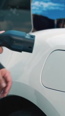 İş dünyasındaki ilerici adam elektrik yükleme istasyonundan doğal şelale ve akış geçmişi olan elektrikli araba giyer. Enerji sürdürülebilirliği kavramı.