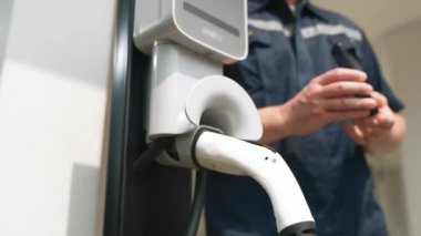 Teknisyen ev EV şarj istasyonu kurar, müşteri akıllı telefonunda şarj durumunu izlemek ve şarj takvimlerini evde ayarlamak için EV uygulamasına hizmet desteği sağlar. Titiz