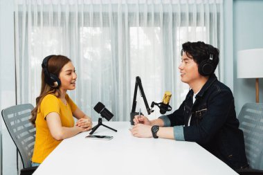 Gülümseyen radyo etkili sunucusu kulaklık takıyor kadın konuşmacı ile röportaj yapıyor sosyal medya internet sitesinden dinleyicilere bilgi paylaşıyor stüdyo kaydında sabah canlı yayın kanalı. İnfobahn.