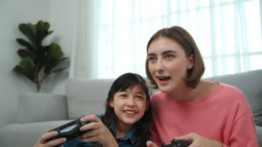 Kafkas anne ve kızı oturma odasında oturup oyun oynuyorlar. Mutlu anne, elinde joystick tutarken akıllı Asyalı kızla vakit geçiriyor. Oyun oynamaktan zevk alıyor. Yaşam tarzı konsepti. Pedagoji.