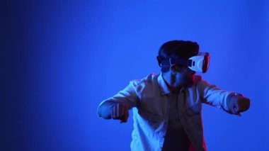 Akıllı oyuncu motosiklet sürerken yarış oyunu oynuyor. Günlük kıyafetleri olan, sanal gerçeklik gözlüğü takan ve meta veriye veya sanal dünyaya giren bir erkek model. Teknoloji. Aygıt.