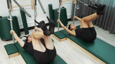 Bir grup müşteri, çekirdek dayanıklılığını ve bacak bağını geliştirmek için Cadillac reformatör makinesinde pilates egzersizleri yapıyor. Sağlıklı müşterilerin daha düşük poz verip kaldırma pozlarının üst görüntüsü. Sağlıklılık. Alışkanlık.