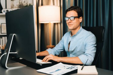 Akıllı iş adamı iş paragrafı dinamik pazarlama analizi planını analiz ediyor. Kağıt kağıtları ve bilgisayar monitörü raporlarını gece evdeki belge verileriyle karşılaştırmak için hazırlıyor. Bireysel.