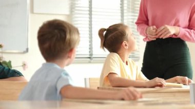 Beyaz bir çocuk ödevlerini yaparken ve açıklama dinlerken güzel bir öğretmen sınavı açıklıyor. Sınıfta not alırken ya da kağıda cevap yazarken öğretmenine bakan sevimli bir çocuk. Pedagoji.