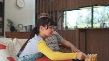 Grandfather and granddaughter eat french fries watch interesting entertainment on TV. Senior use technology communicate with young generation cross generation gap strengthen family bond. Divergence.