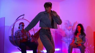 Çok kültürlü bir arkadaş kürsüde otururken Asyalı yetenekli bir dansçı modern müziğe geçiyor. Profesyonel dansçı, hipster takımı tezahürat yaparken ve desteklerken enerjik adımlar atıyor. Mutluluk.