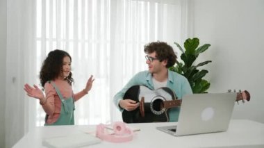 Çekici beyaz bir baba gitar çalarken tatlı bir kız müzik eşliğinde dans ediyor. Mutlu baba ve Amerikalı kız birlikte vakit geçirirken akıllı çocuk müzik yapıyor. Aile eğlence konsepti. Pedagoji.