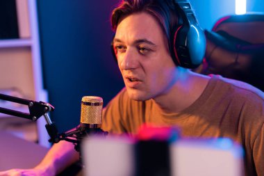 Oyun kanalı, online oyun oynayan akıllı flamalı oyun sunucusu, kulaklık takan, neon ışıklandırma odasındaki takım oyuncusuyla akıllı telefondan canlı yayında konuşan izleyiciler. Bireysel.