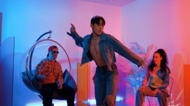 Çok kültürlü bir arkadaş kürsüde otururken Asyalı yetenekli bir dansçı modern müziğe geçiyor. Profesyonel dansçı, hipster takımı tezahürat yaparken ve desteklerken enerjik adımlar atıyor. Mutluluk.