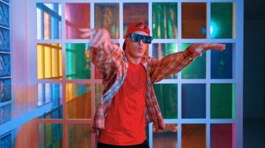 Komik break dansçı kameraya bakarken hiphop 'a doğru serbest adım atıyor. Çılgın mutlu hipster dans edip sokak dansı yaparken Led ışığında günlük kıyafet ve güneş gözlüğü takıyor. Mutluluk.