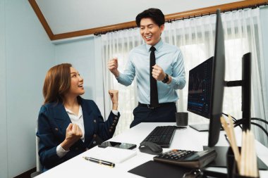 Başarılı gülümseyen Asyalı iş ortakları borsa veritabanında kârlı bir proje için el ele tutuşuyorlar. Yan görüntüdeki modern ev ofisinde resmi takım elbise giyiyorlar. İnfobahn.