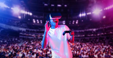 Yetişkinlerin elinde joystickle VR gözlükleri varken stadyumda arka planda bulanık oyunlar oynamaktan zevk alıyorlar. Afrikalı adam kontrol etmeyi ve artırılmış gerçeklik teknolojisini kullanmayı seviyor. Yaratıcılık.