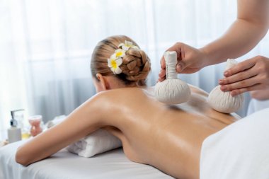 Sıcak bitkisel top spa masaj vücut tedavisi, masör kadın vücuduna nazikçe şifalı bitki torbası bastırıyor. Aromaterapi dinlenme sükuneti ve sükuneti kaplıca salonundaki atmosferi aydınlatıyor. Sessiz.