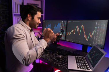 Akıllı tüccar işadamı, karanlık oda gecesinde neon ışıklı ofisteki arama pazarında yüksek kârla ekranda bilgisayar ve bilgisayar üzerinde dinamik borsa yatırımları üzerinde yoğunlaşıyor. Tahmin et..