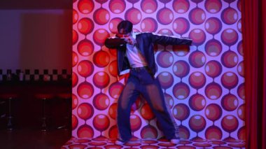 Asyalı break dansçı serbest stile geçiyor ve balon arka planlı kameraya bakıyor. Profesyonel hippi gündelik kıyafet giyer ve gözlük takar. Mutluluk.