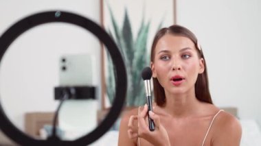 Sosyal medya için güzellik ve kozmetik video içeriği hazırlayan genç bir kadın. Güzellik blogcusu kameraya gülümserken seyircilere ve takipçilere güzellik bakımını gösteriyor. Düzenle