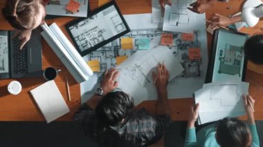 Yöneticinin proje planı yazması ve toplantıda oturması. Bilgisayarlı ve teçhizatlı ev inşaatı hakkında planlar yapan ve paylaşan iş adamlarının havadan görüşü. Sempozyum.