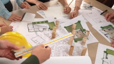 Mimari belge, ölçüm aracı ve ahşap blokların modern ofiste etrafa saçıldığı bir masa üzerinde yapı inşaatı ile ilgili mimar ve güvenlik mühendisi tartışması. Tanımlama.