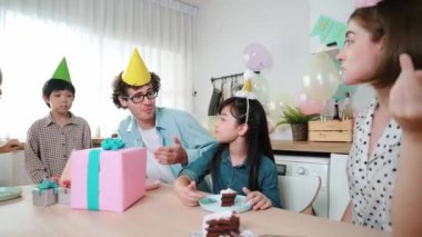 Çekici aile, modern mutfakta masaya konmuş renkli balonla süslenmiş bir şekilde konuşurken kızının doğum gününü kutluyor. Mutlu Asyalı kız gülümseyen ailesiyle pasta yiyor. Pedagoji.