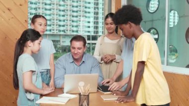 Başarılı bir proje için öğrencileri teşvik etmek ya da kutlamak için yetenekli bir öğretmen alkışlıyor. Çeşitli çocuklar profesyonel eğitmenin etrafında dururken el çırpıyorlar. Öğretim