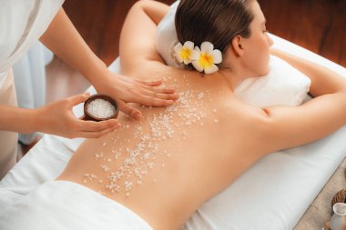 Lüks spa salonlarında sıcak mum ışığında cilt bakımı yaptıran kadın müşteri. Sağlık Spa vücut fırçasında tuz temizleme güzellik tedavisi. Sessiz.