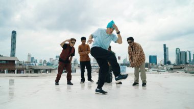 Profesyonel break dans takımı çatıda çok kültürlü arkadaşlar varken break dans alıştırması yapıyor. Genç modern dans grubu hip hop hareketi yapıyor. Tarz, moda, aksiyon. Açık hava sporu 2024 hiphop..