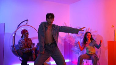 Çok kültürlü bir arkadaş kürsüde otururken Asyalı yetenekli bir dansçı modern müziğe geçiyor. Profesyonel dansçı, hipster takımı tezahürat yaparken ve desteklerken enerjik adımlar atıyor. Mutluluk.