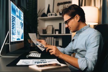 Akıllı bir işadamının elinde kağıt tutarak, gece vakti modern yurt içi ofisindeki şirket toplantısı için müşteri hedefini analiz etmek üzere kalemle paragraf dinamik veritabanı oluşturduğunu düşünüyorum. Bireysel.