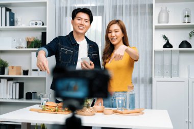 Aşçılar, sosyal medya yemek programı kanalı canlı yayın menü yemeği salatası, kepekli çörek ve video kameradan hamburger kaydı için telefonda yorum okuyorlar. İnfobahn.