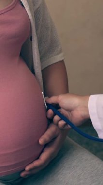 Mutlu hamile kadın, jinekolog doktoru hastanede ya da klinikte hamilelik danışmanlığı için ziyaret ediyor. Doktor, bebek ve anne sağlığı kontrolü için hamile karnı muayene ediyor. Jinekoloji konsepti.