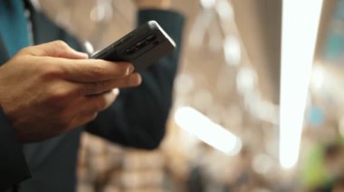 İş adamının elleri trende insanlarla çevriliyken telefona bakarken yakın çekim. Kafkas proje yöneticisi e-postaları kontrol ediyor, arka planı bulanık pazarlama stratejisi planlıyor. Sevinçli..